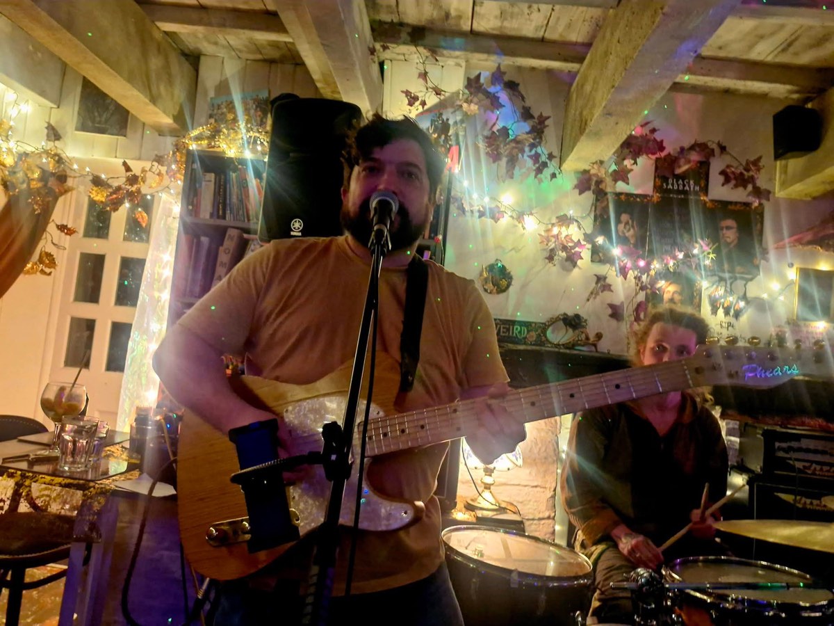 A band playing live, singer on electric guitar with a drummer behind