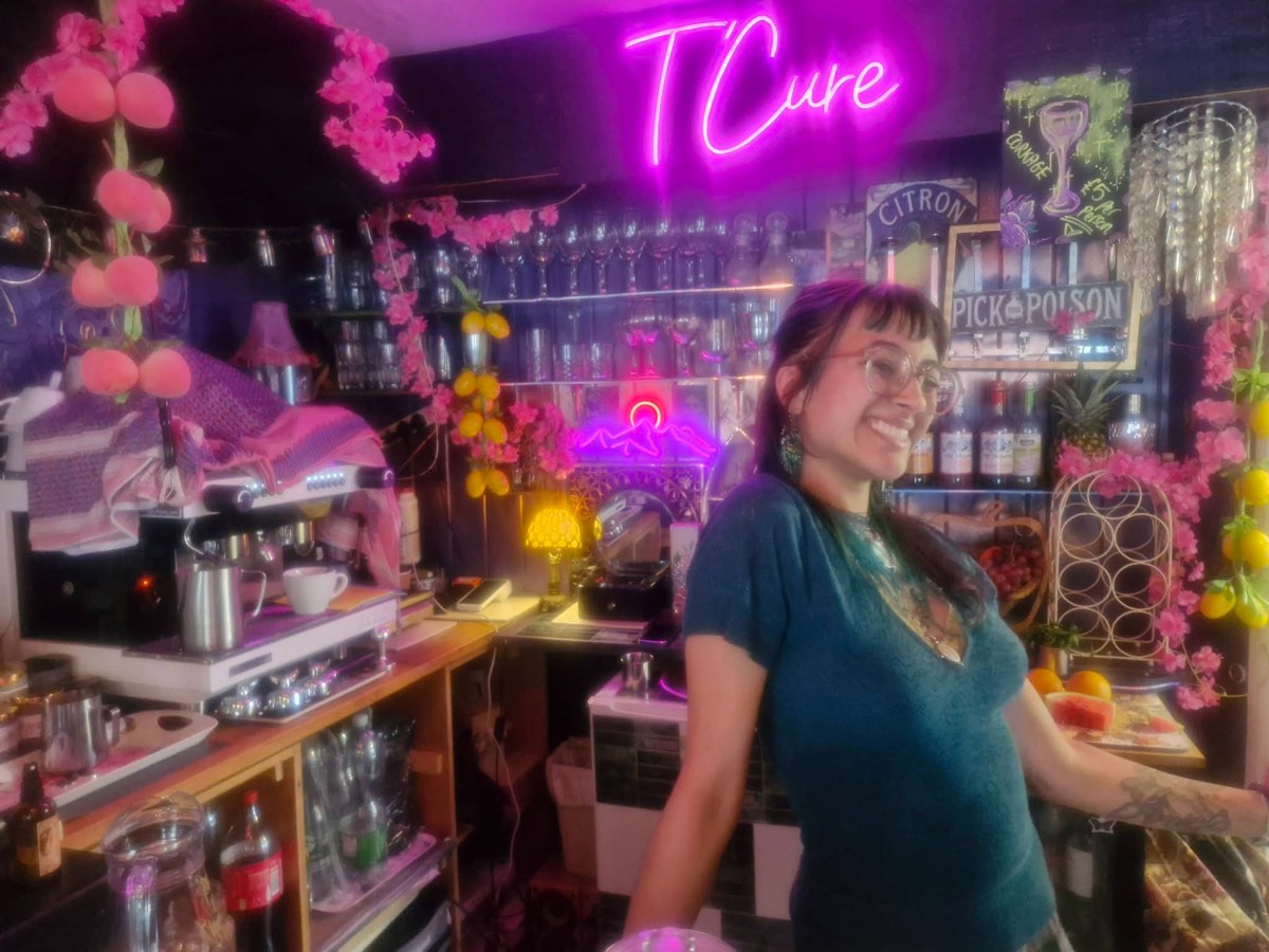 Smiling at the bar under the pink neon T'cure sign, with blossom garlands and lemons