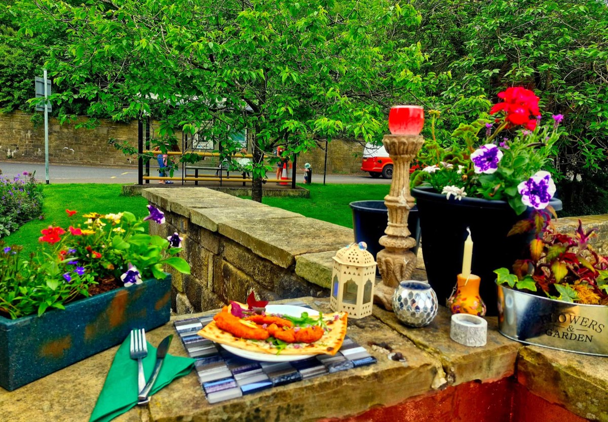 Flatbread with crispy fritters served on the stone wall among flower boxes