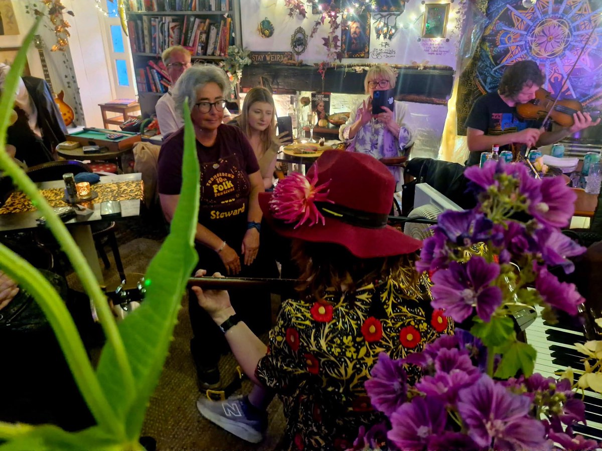 A folk session with fiddle and guitar, guests filming on their phones