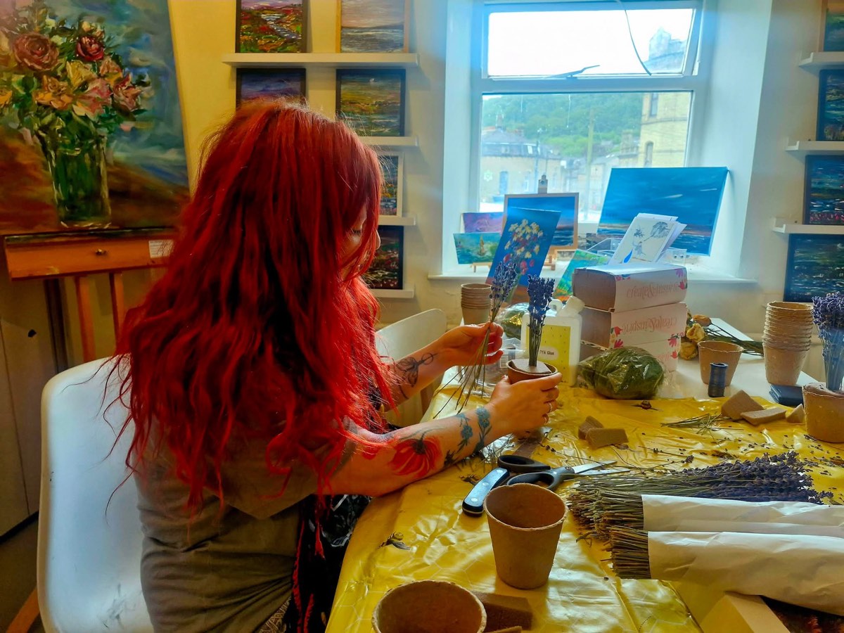 A craft workshop making dried lavender pots, paintings on the wall behind